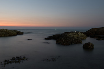 Fototapeta na wymiar Beautiful landscape sunset in the sea with stones rocks on long exposure