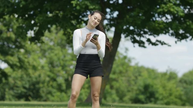 Attractive young woman cheerfully on her phone outdoors