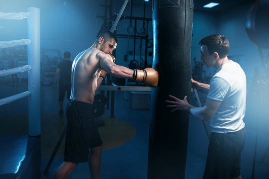 Man in black handwraps exercises with bag in gym
