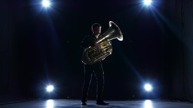 Musician in dark studio with spotlights playing tuba slow jazz