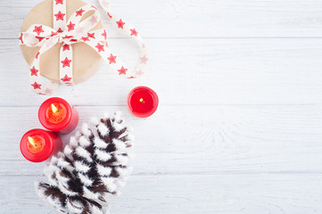 Gift in kraft box with red stars ribbon, lit candles and decorations