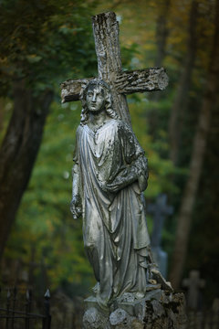 Cross and angel statue on gravestone at cemetery. Rest in peace. In memoriam