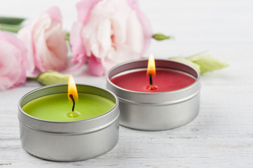 Pink eustomas on a white wooden board, lit candles