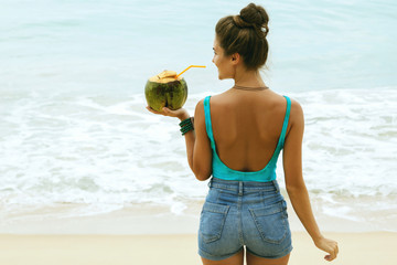 Woman with a coconut drink on the beach