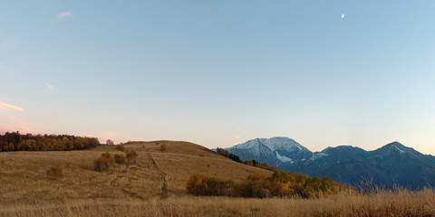 Autumnal subalpine landscape at sunset with snowy mountain peaks, forest, and meadow. Caucasus. Russia. The Caucasian reserve. Pasture Abago