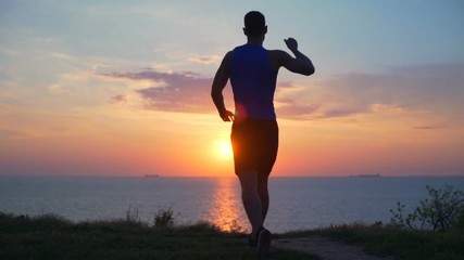 Young strong healthy winner man raising arms celebrating dawn sea slow motion