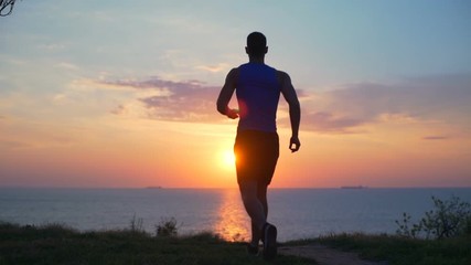 Young strong healthy man raising arms celebrating win dawn sea slow motion