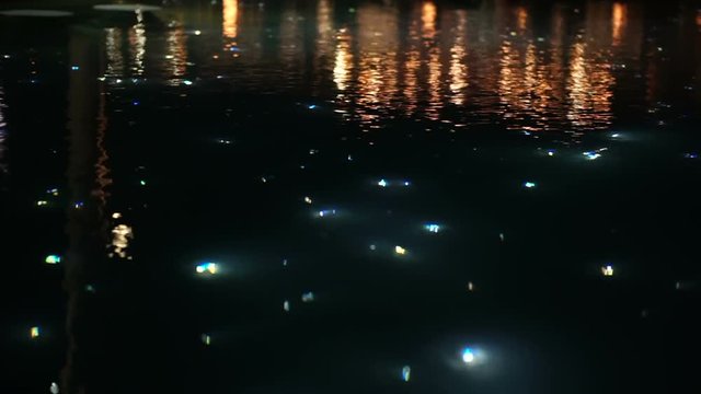 Slow motion blur beautiful light of starry night pool, illuminate fiber optic light next to restaurant 