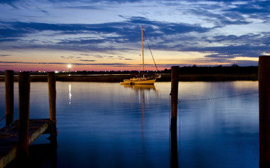 Fototapeta na wymiar Sailboat in Shimmering Water at Dusk