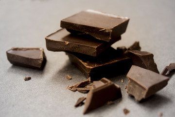Pieces of natural dark chocolate on wooden table