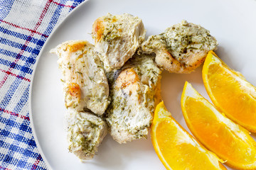 Boiled chicken breast with dill and orange slices on a white plate