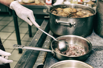 Chef is frying lamb slices in oil, toned image