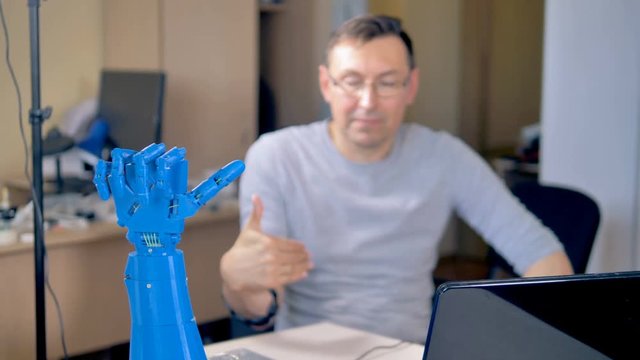 An engineer gives direction to a bionic hand.