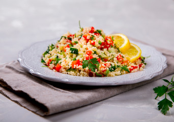 Tabbouleh salad with couscous on the plate.Traditional middle eastern or arab dish.Vegetarian.Parsley,pepper,cucumber,tomato,lemon.Middle eastern meze.Food or Healthy diet concept.Copy space for Text.