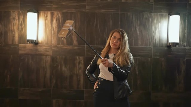 A young blonde girl makes a selfie photograph using a stick of stick. Live and create stories for social networks.
