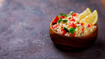 Tabbouleh salad with couscous on the plate.Traditional middle eastern or arab dish.Vegetarian.Parsley,pepper,cucumber,tomato,lemon.Middle eastern meze.Food or Healthy diet concept.Copy space for Text.