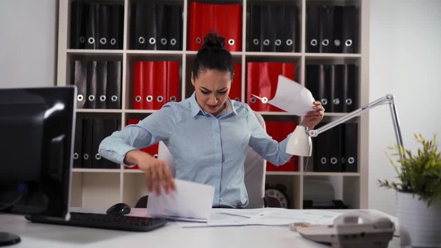 Portrait of female entrepreneur sitting at the office table with scared and terrified expression, working on the computer, documents, tablet pc, mobile phone. No time to work. Hurry Up concept. 4k.