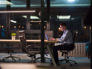 man working on laptop in dark office