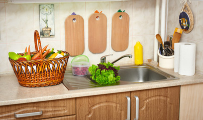 vegetables and fresh greens in basket in kitchen interior, healthy food concept