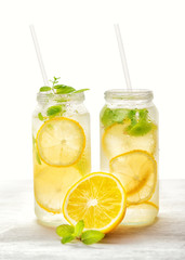 lemonade with fresh lemon and twig mint with drinking straw on white background