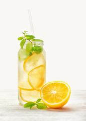 lemonade with fresh citrus lemon and twig mint with drinking straw on wood background