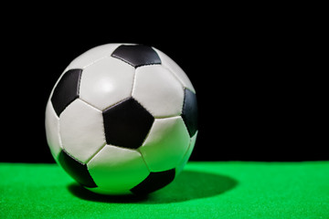 soccer ball on green grass over black background, close up