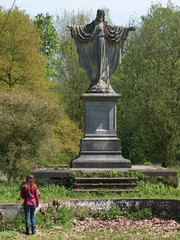 Girl soul-searching in front of a statue of Jesus Christ in an abandoned park.