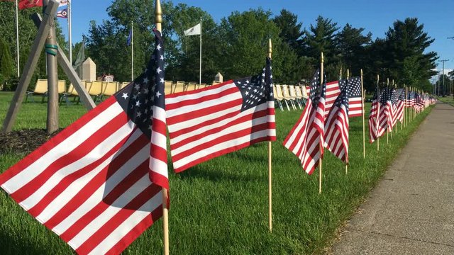 Row of American Flags in a field on beautiful warms summer afternoon near veterans monument