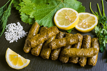 Delicious stuffed grape leaves (the traditional dolma of the mediterranean cuisine) on black dish...