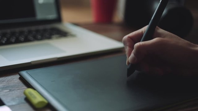 Designer working on a laptop with a graphics tablet. Closeup