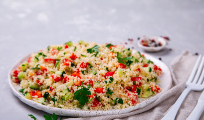 Tabbouleh salad with couscous on the plate.Traditional middle eastern or arab dish.Vegetarian.Parsley,pepper,cucumber,tomato,lemon.Middle eastern meze.Food or Healthy diet concept.Copy space for Text.