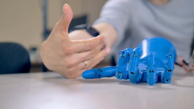 Human arm fingers making example motions for robotic ones.