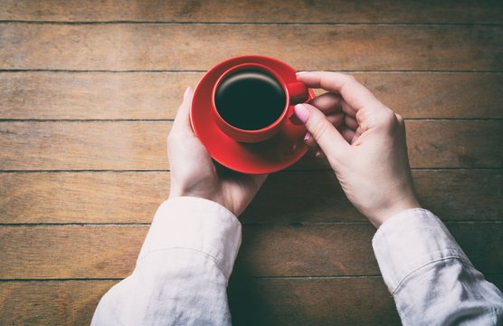 woman hands holding little red cup of coffee