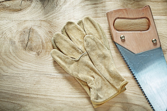 Protective gloves handsaw on wooden board construction concept