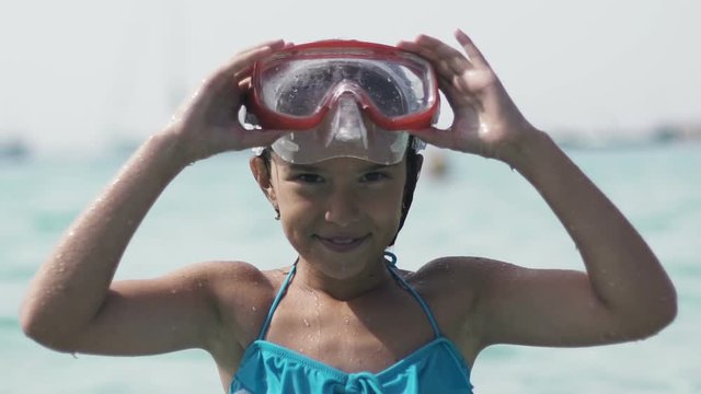 Little girl in underwater mask springs out of sea water. Slow motion 120 fps