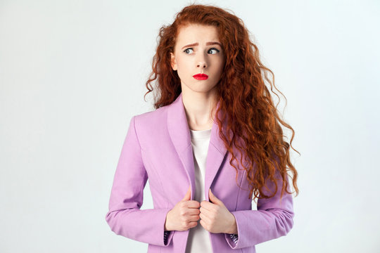 Portrait of thoughtful beautiful business woman with red - brown hair and makeup in pink suit. thinking and looking away, studio shot on gray background.