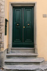 Fototapeta na wymiar Green door with three stone steps in front in Fiesole, Italy