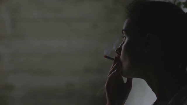 Woman smokes a cigarette at night. Slow motion.