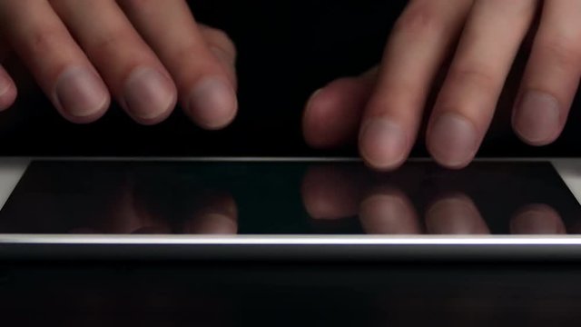 Man types text message on electronic tablet. Hands close-up.