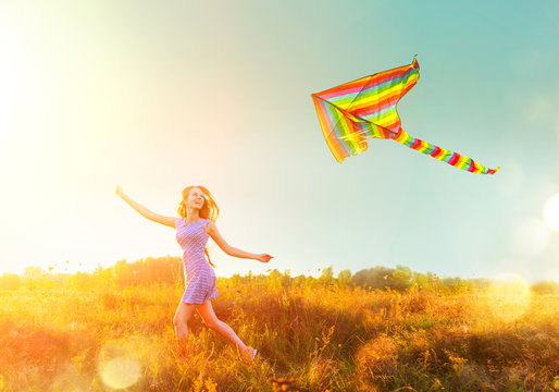 Beauty girl in short dress running with flying colorful kite over clear blue sky. Freedom concept. 
