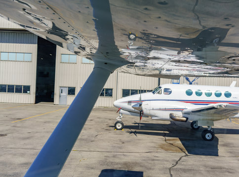 View Of Light Aircraft From Underneath A Plane On Sunny Day.