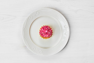 Single cupcakes decorated with pearls and hearts on wooden table