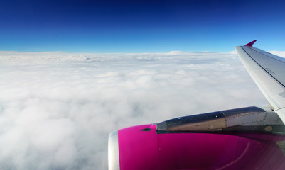 Fototapeta na wymiar Part section of pink aeroplane fuselage flying above the clouds.
