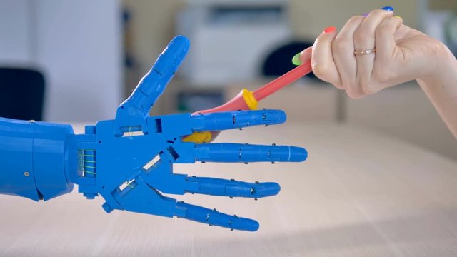 A bionic hand takes a screwdriver.