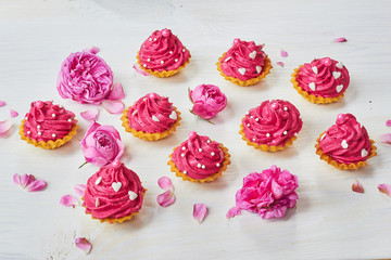 Pink dessert on white wooden table with pink roses