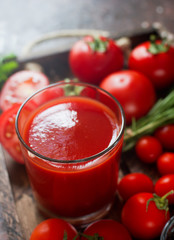 glass of tasty organic tomato juice and fresh tomatoes and herbs on wooden tray in rustic style. Selective focus, healthy lifestyle