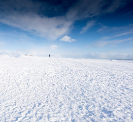 Naklejka na ściany i meble Person standing in snow covered landscape and blue sky, Iceland, Europe.