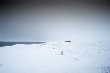 Cosy log cabin in snow covered landscape, distant, Iceland, Europe.