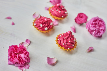 Pink dessert on white wooden table with pink roses