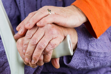 Elderly hands resting on stick